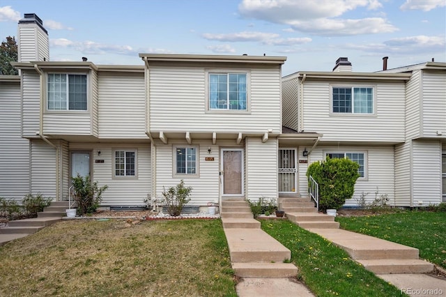multi unit property with a front yard, a chimney, and entry steps