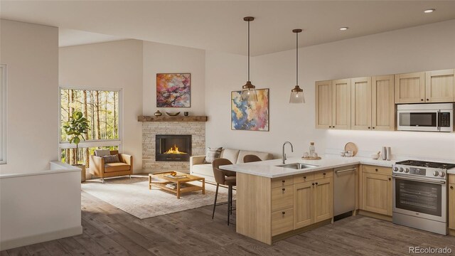 kitchen featuring appliances with stainless steel finishes, dark wood-type flooring, kitchen peninsula, a kitchen bar, and sink