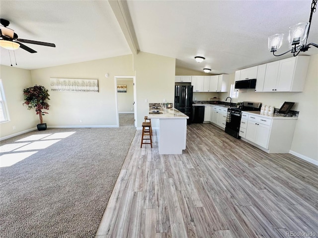 kitchen featuring white cabinets, light wood-type flooring, black appliances, a kitchen bar, and vaulted ceiling with beams