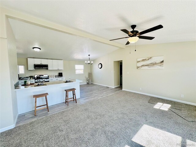 kitchen featuring white gas range oven, white cabinets, kitchen peninsula, a breakfast bar area, and vaulted ceiling with beams