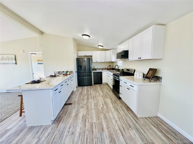 kitchen featuring vaulted ceiling with beams, a breakfast bar area, white cabinets, and black appliances