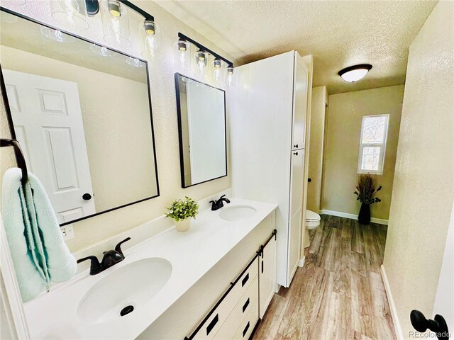 bathroom featuring a textured ceiling, hardwood / wood-style flooring, vanity, and toilet