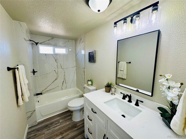 full bathroom featuring vanity, a textured ceiling, wood-type flooring, toilet, and tiled shower / bath