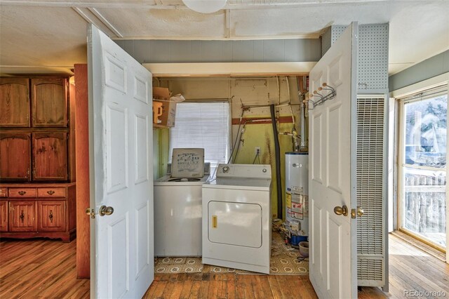 clothes washing area featuring washing machine and dryer, light wood-type flooring, a textured ceiling, and water heater