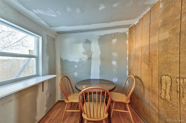 dining area with wood-type flooring and wood walls