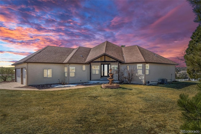 view of front facade featuring a garage, driveway, a front lawn, and stucco siding