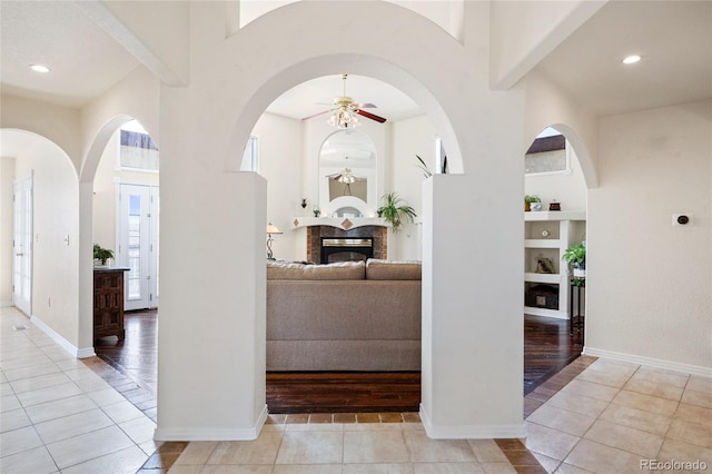 corridor featuring tile patterned flooring, built in shelves, a healthy amount of sunlight, and baseboards