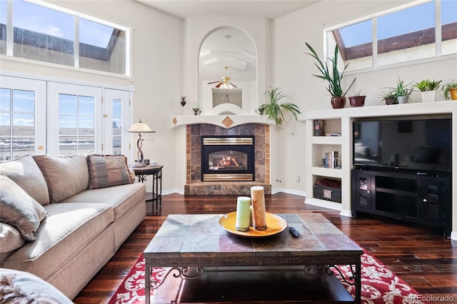 living room with a wealth of natural light, a tile fireplace, baseboards, and wood finished floors