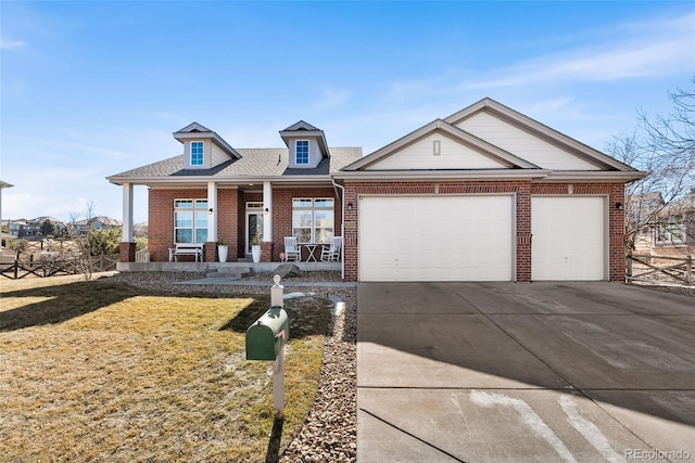 view of front of home with an attached garage, covered porch, brick siding, concrete driveway, and a front yard