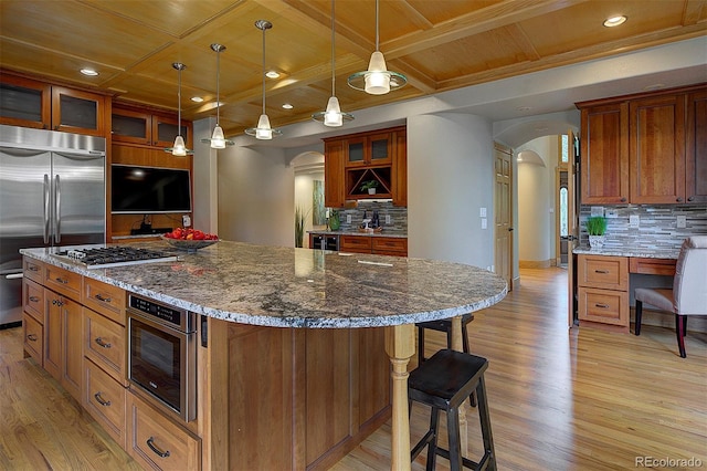 2191 Baldy Ln, Evergreen, CO 80439 - kitchen with arched walkways, appliances with stainless steel finishes, a wooden ceiling with exposed beams, light wood-style flooring, and decorative backsplash
