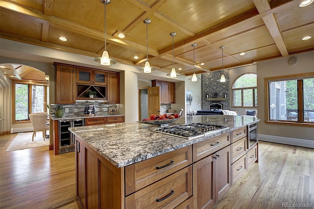 2191 Baldy Ln, Evergreen, CO 80439 - kitchen with stainless steel gas cooktop, wine cooler, arched walkways, light wood-type flooring, and a wooden ceiling with exposed beams