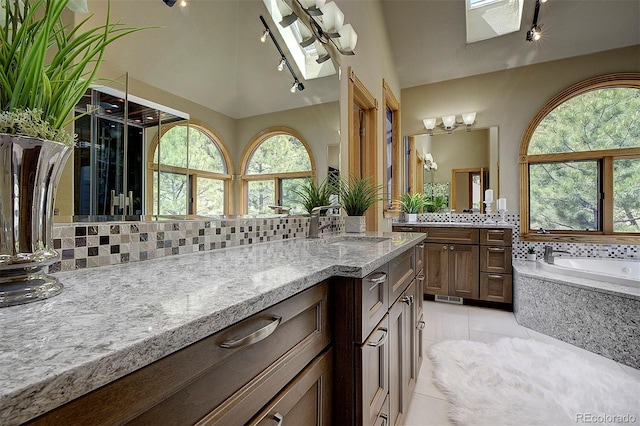 2191 Baldy Ln, Evergreen, CO 80439 - full bathroom with backsplash, plenty of natural light, vanity, a skylight, and lofted ceiling