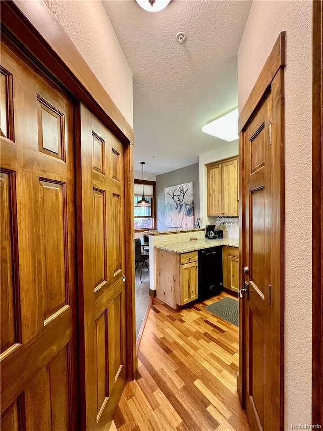 2104 Blue Sky Trl Unit 2-104, Granby, CO 80446 - kitchen with black dishwasher, a peninsula, light wood-type flooring, a textured ceiling, and brown cabinets