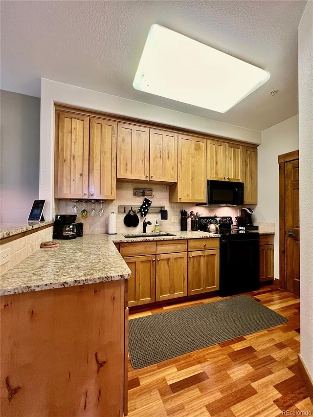 2104 Blue Sky Trl Unit 2-104, Granby, CO 80446 - kitchen featuring black appliances, a peninsula, light wood finished floors, light stone counters, and tasteful backsplash