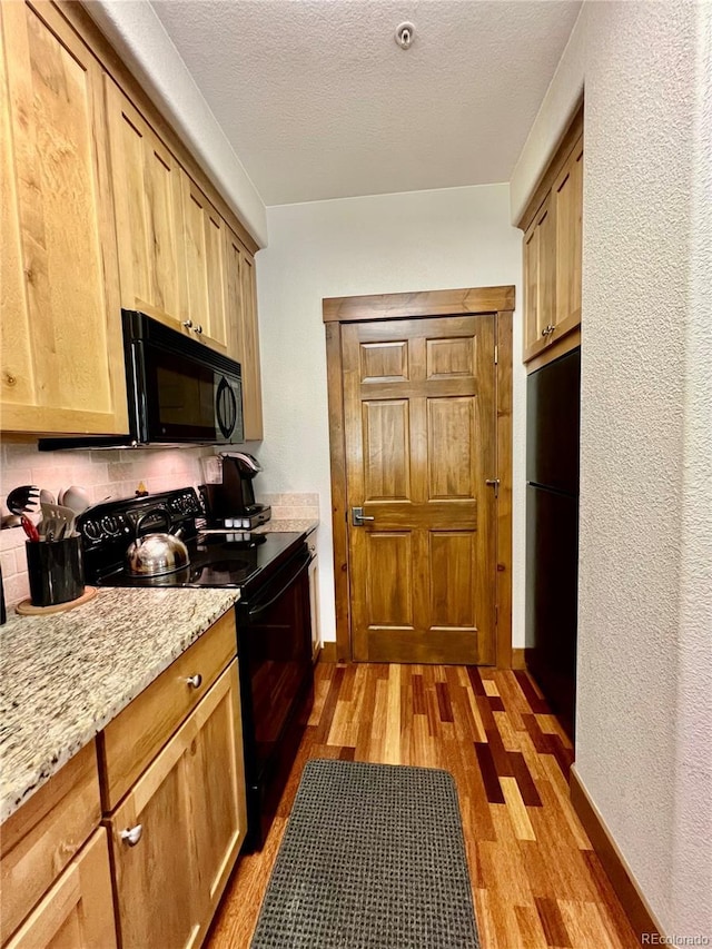 2104 Blue Sky Trl Unit 2-104, Granby, CO 80446 - kitchen with black appliances, light wood-type flooring, a textured wall, and light stone countertops
