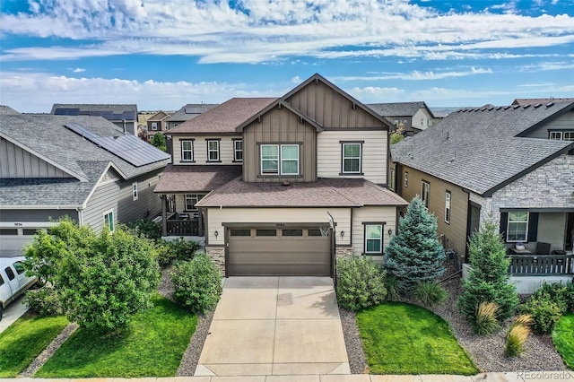 craftsman-style home featuring an attached garage, stone siding, driveway, a residential view, and board and batten siding