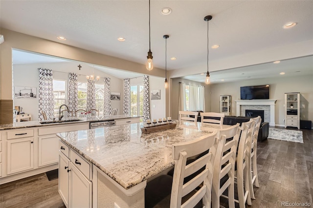 kitchen with light stone counters, recessed lighting, a sink, open floor plan, and dark wood finished floors