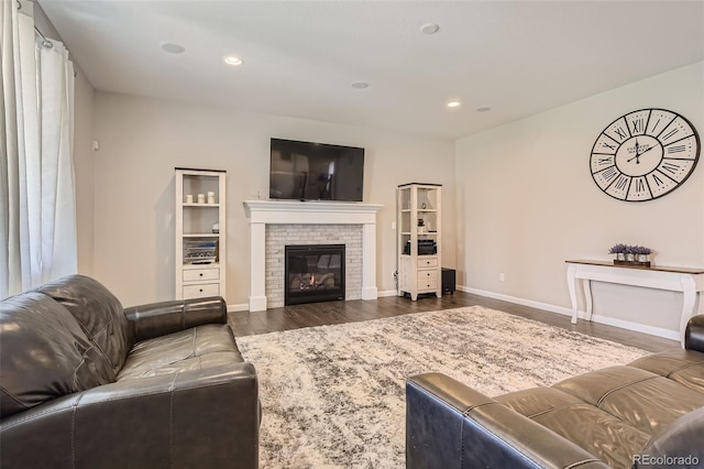 living room featuring baseboards, a brick fireplace, wood finished floors, and recessed lighting