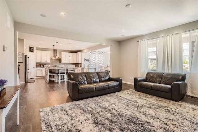 living room with dark wood-style flooring, recessed lighting, visible vents, and baseboards