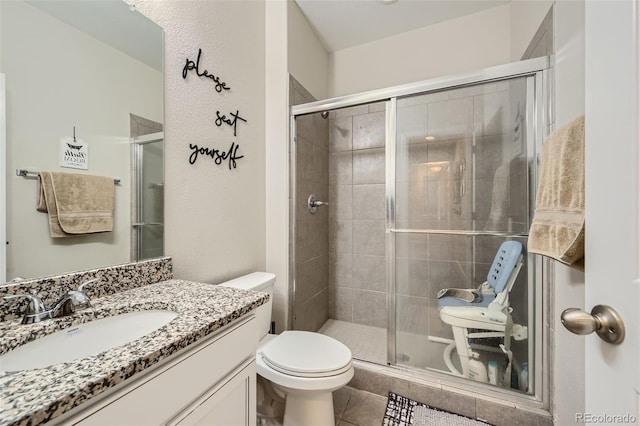 bathroom with tile patterned floors, a shower stall, toilet, and vanity