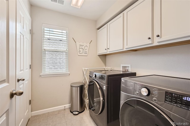 laundry room featuring light tile patterned floors, visible vents, baseboards, washer and dryer, and cabinet space