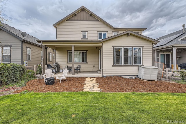 back of house featuring a yard, a patio, board and batten siding, and fence