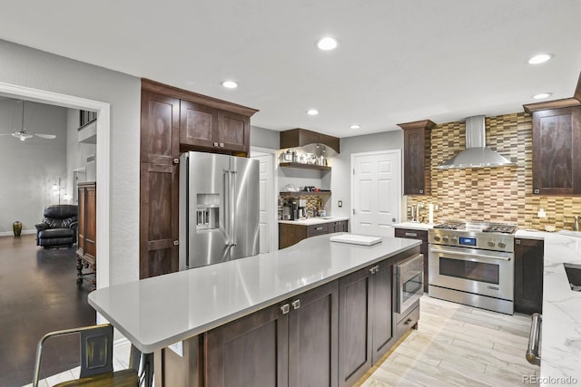 kitchen with a center island, light hardwood / wood-style flooring, high quality appliances, and wall chimney range hood