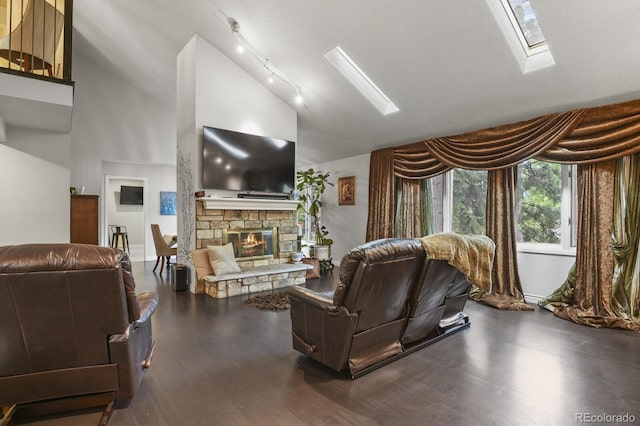 living room with track lighting, high vaulted ceiling, a stone fireplace, and dark wood-type flooring