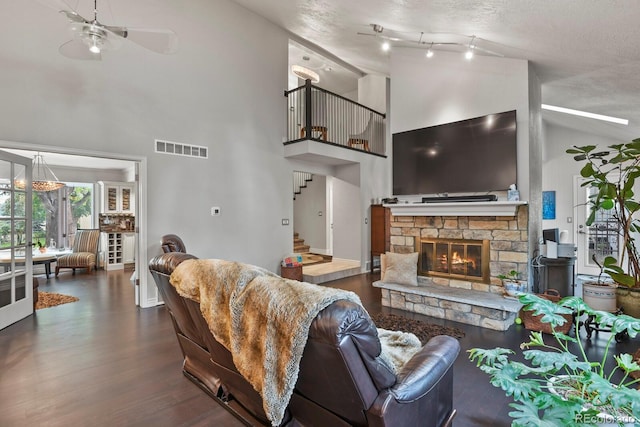 living room featuring high vaulted ceiling, ceiling fan, a fireplace, a textured ceiling, and wood-type flooring