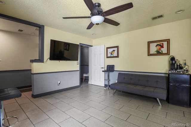 living room with ceiling fan and a textured ceiling