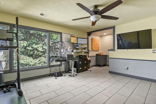 tiled office space featuring ceiling fan and a textured ceiling