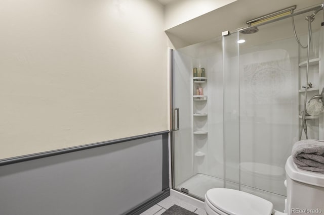 bathroom with tile patterned flooring, toilet, and a shower with door