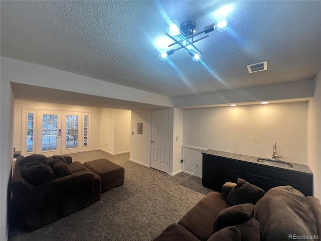 carpeted home theater with french doors, wet bar, and a textured ceiling