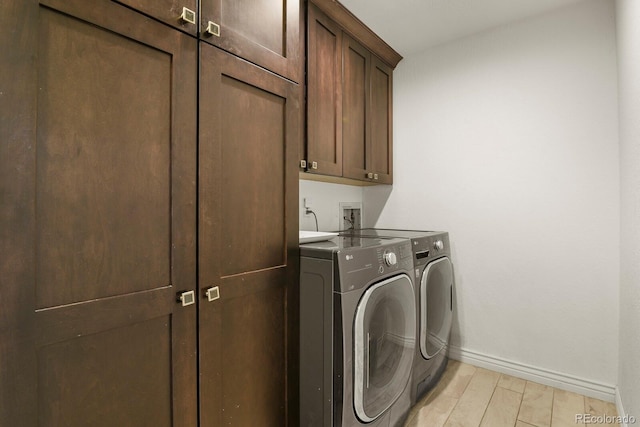 clothes washing area with separate washer and dryer, cabinets, and light wood-type flooring