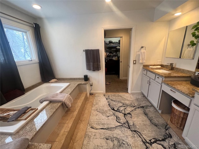 bathroom featuring tiled tub and vanity