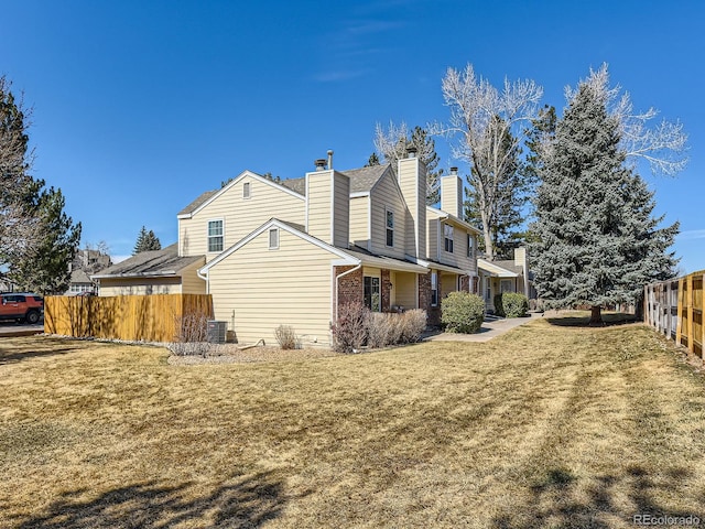 view of home's exterior with a yard, central AC, fence, and a chimney