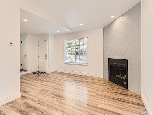 unfurnished living room with recessed lighting, baseboards, light wood-style flooring, and a tiled fireplace