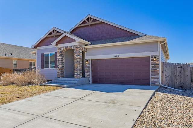 craftsman inspired home with stone siding, fence, roof with shingles, concrete driveway, and an attached garage