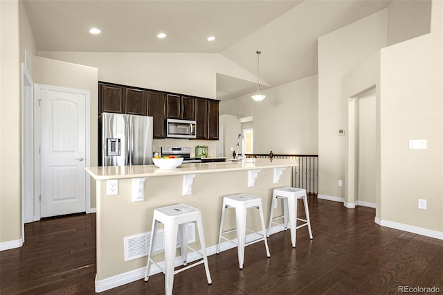 kitchen featuring dark wood-style floors, a breakfast bar area, stainless steel appliances, and an island with sink