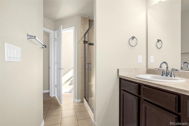 bathroom with baseboards, vanity, a shower stall, and tile patterned flooring