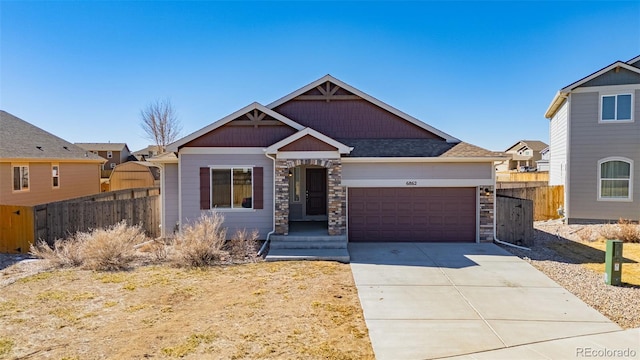 craftsman house featuring concrete driveway, a garage, fence, and stone siding