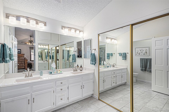 1121 W Kettle Ave, Littleton, CO 80120 - bathroom with double vanity, a textured ceiling, toilet, connected bathroom, and a ceiling fan