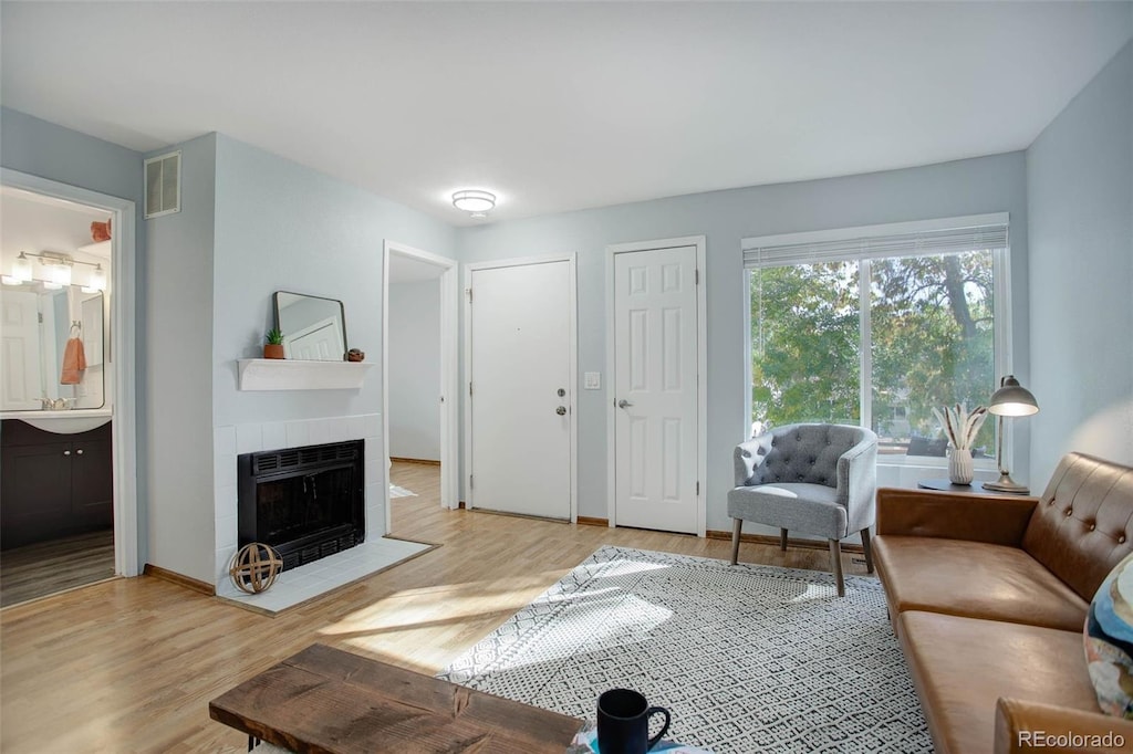 living room with a tiled fireplace and hardwood / wood-style flooring