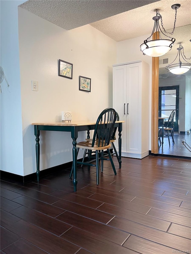 dining space with dark hardwood / wood-style flooring and a textured ceiling