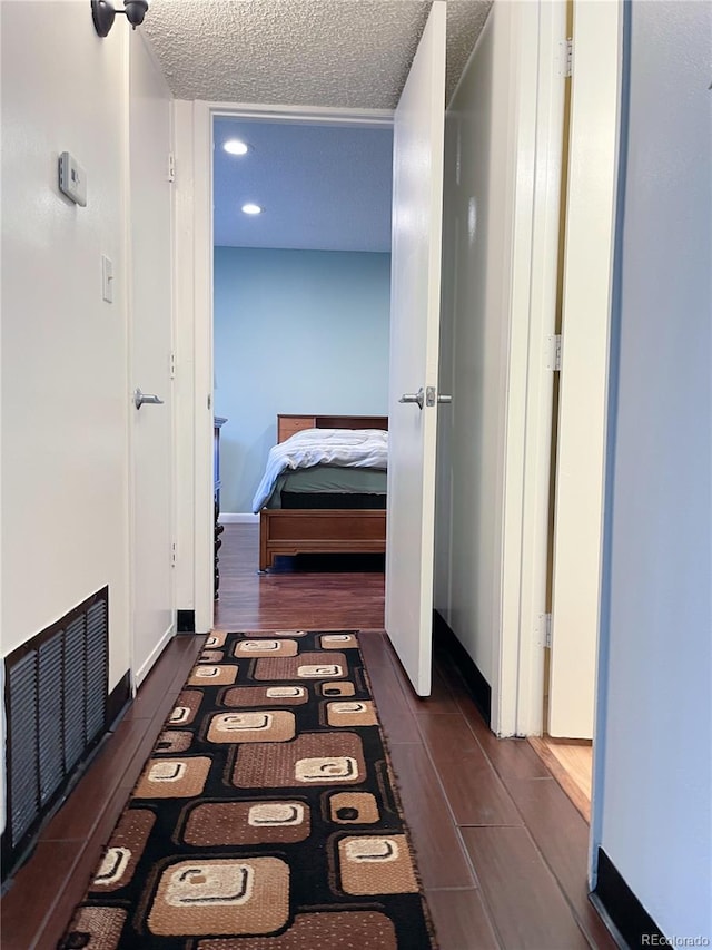 corridor with dark hardwood / wood-style flooring and a textured ceiling