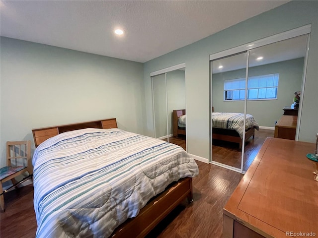 bedroom with dark wood-type flooring and multiple closets