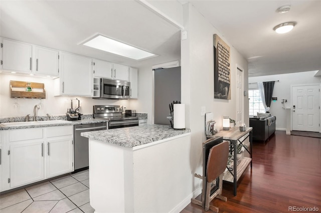 kitchen with sink, light hardwood / wood-style flooring, stainless steel appliances, and white cabinets