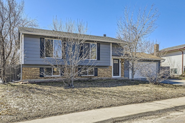 split level home featuring a garage, brick siding, and driveway