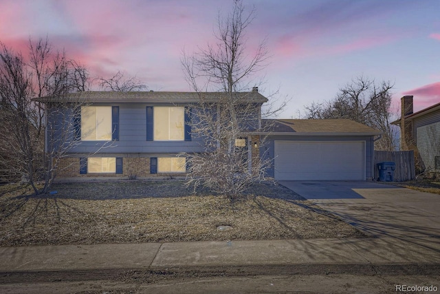 view of front of house with driveway, an attached garage, fence, and brick siding