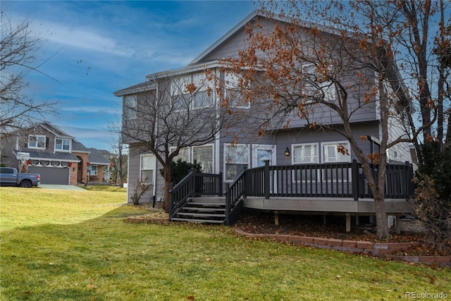 rear view of house featuring a garage, a deck, and a yard